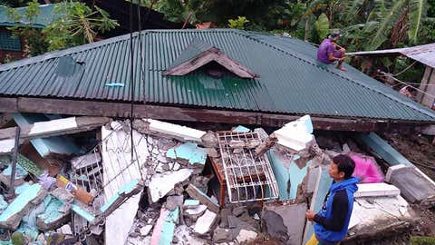 Residents stand next to their collapsed house a day after a 6.5 magnitude earthquake hit the town of Tongonan, Leyte province, central Philippines on July 7, 2017. (LITO BAGUNAS/AFP/Getty Images)