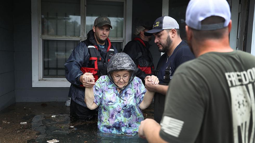 Volunteer rescuer workers help woman from her home inundated with the flooding of Hurricane Harvey on August 30, 2017.