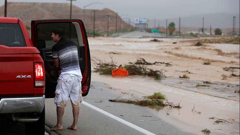 A man stands by a truck after walking through floodwaters in Moapa, Nev. Monday, Sept. 8, 2014.
