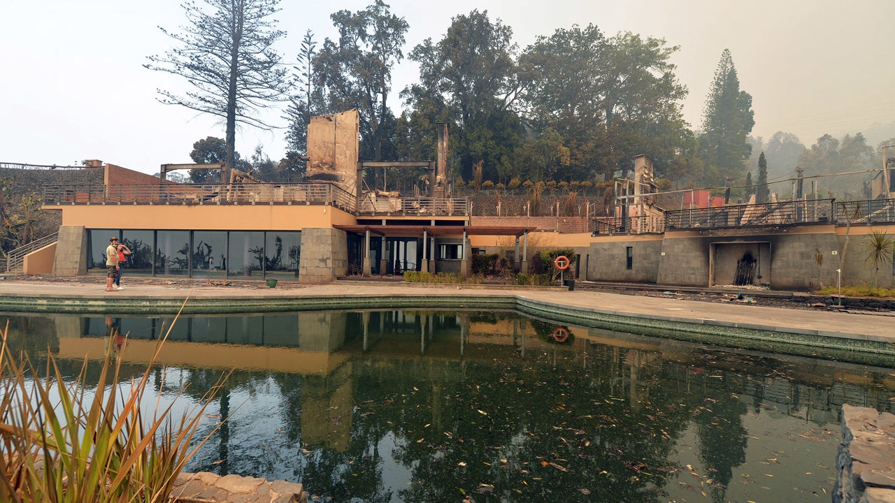 A couple looks at the burnt ruins of the Choupana Hills hotel in the outskirts of Funchal, the capital of Portugal's Madeira island, Wednesday, Aug. 10 2016. The hotel was caught in the forest fires that are raging in Madeira and have forced the evacuation of more than 1,000 residents and tourists. (AP Photo/Helder Santos)