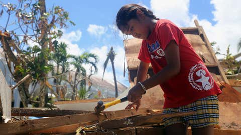 A girl helps her parents repair their storm-damaged home by removing nails from plywood on Saturday, Aug. 8, 2015, in Saipan, Northern Mariana Islands. President Barack Obama has declared the Commonwealth of the Northern Mariana Islands a disaster area and is ordering federal aid to help the U.S. territory in the aftermath of a destructive typhoon. (AP Photo/Daniel Lin)