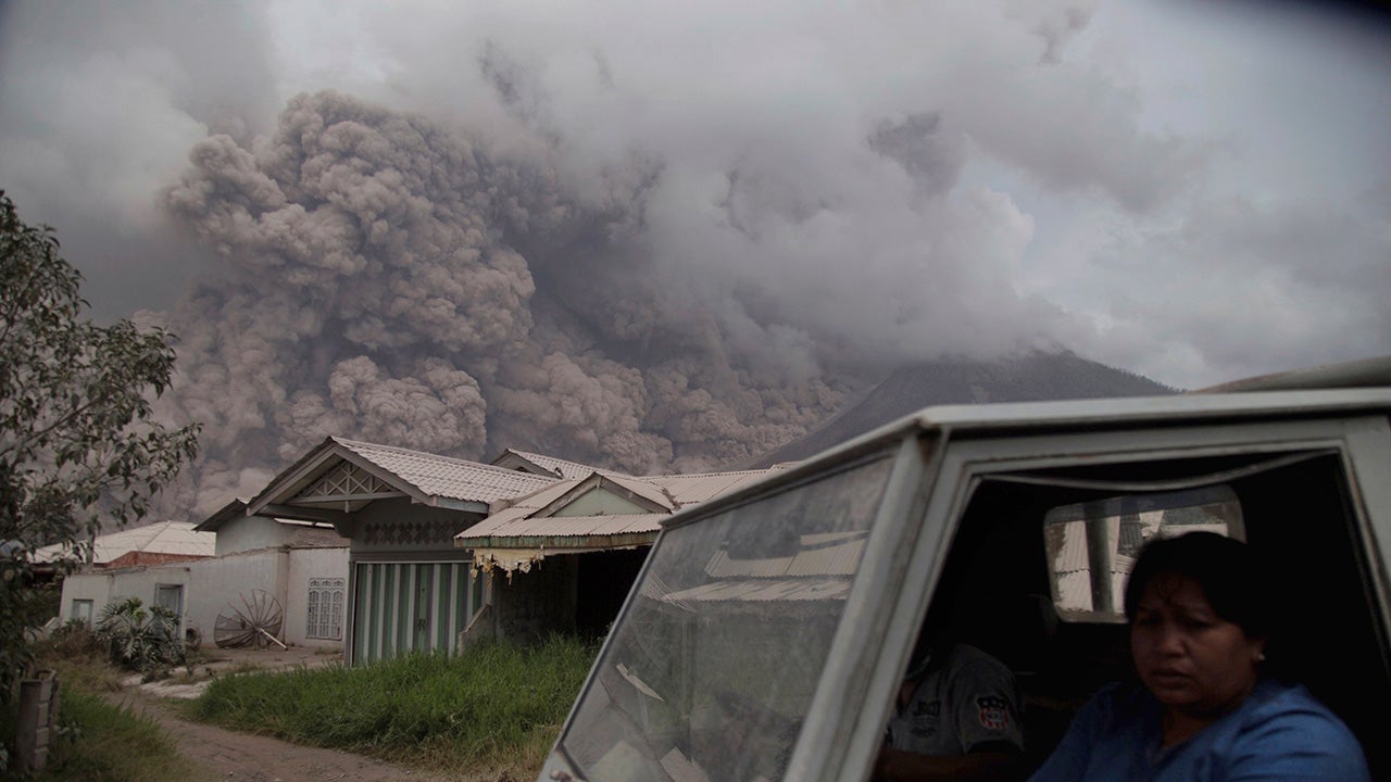 Residents ride in a truck as Mount Sinabung releases pyroclastic flows during its eruption in Karo, North Sumatra, Indonesia, Wednesday, Aug. 2, 2017.  (AP Photo/Endro Rusharyanto)
