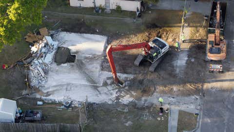 This Aerial photo shows demolition workers picking up the remnants from the home of Jeff Bush, Tuesday, March 5, 2013, in Seffner, Fla. A huge sinkhole opened up under a bedroom in the home last Thursday, Feb. 28, and swallowed Jeff Bush, 37. (AP Photo/The Tampa Bay Times, Dirk Shadd)