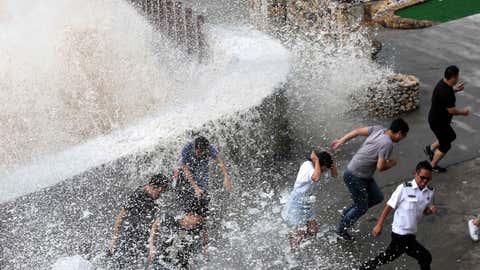 This photo taken on September 14, 2017 shows people reacting as a wave, caused by Typhoon Talim, crashes over a promenade in Wenling in China's eastern Zhejiang province. (STR/AFP/Getty Images)