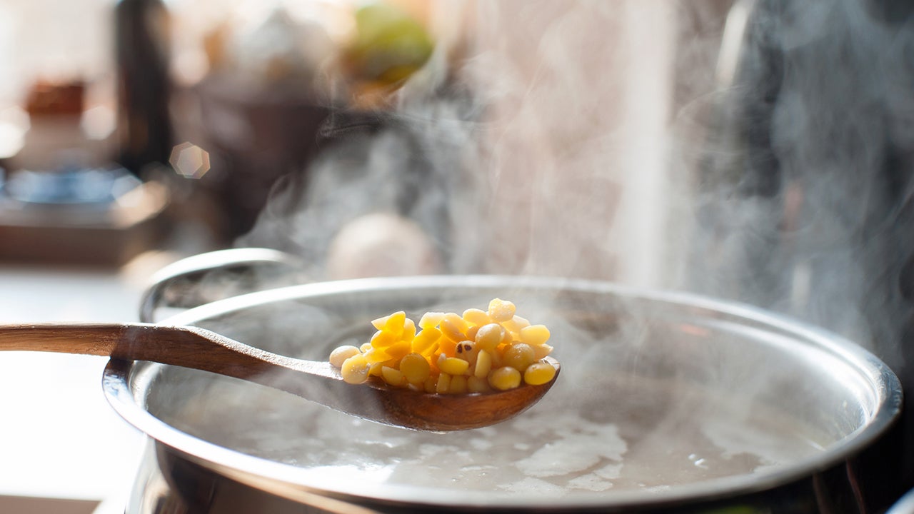 Saucepan and wooden spoon with split pea. Boiling broth with steam. Making soup.