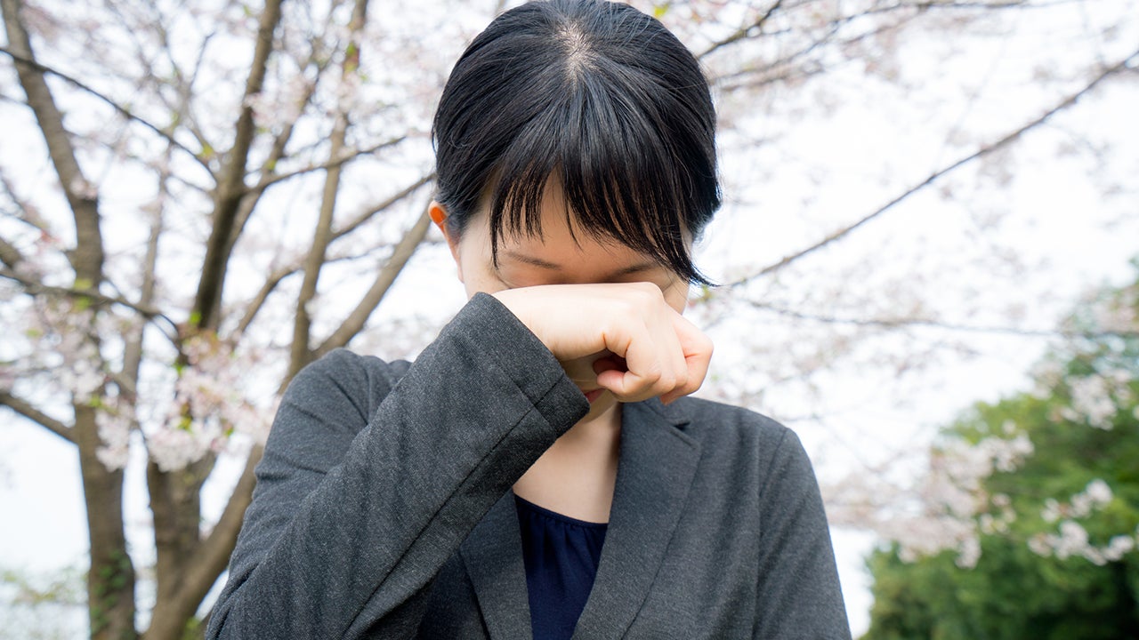 Young businesswoman crying under the cherry blossoms.