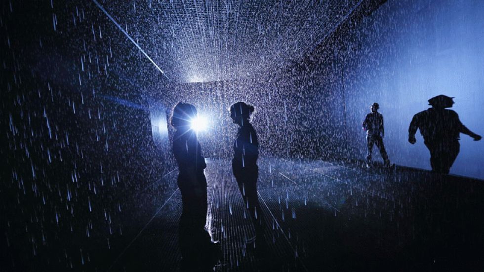 Members of the public experience 'Rain Room,' an art installation by Random International, at the Barbican Centre in London, England. It features a field of falling water that pauses wherever a human body is detected, and will be part of a MoMA PS1 exhibition in NYC. (Photo: Oli Scarff/Getty Images)