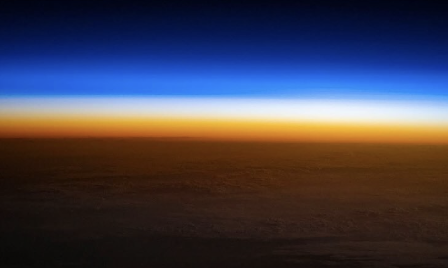 Bands of vivid blue, pink and orange light are seen across the horizon.