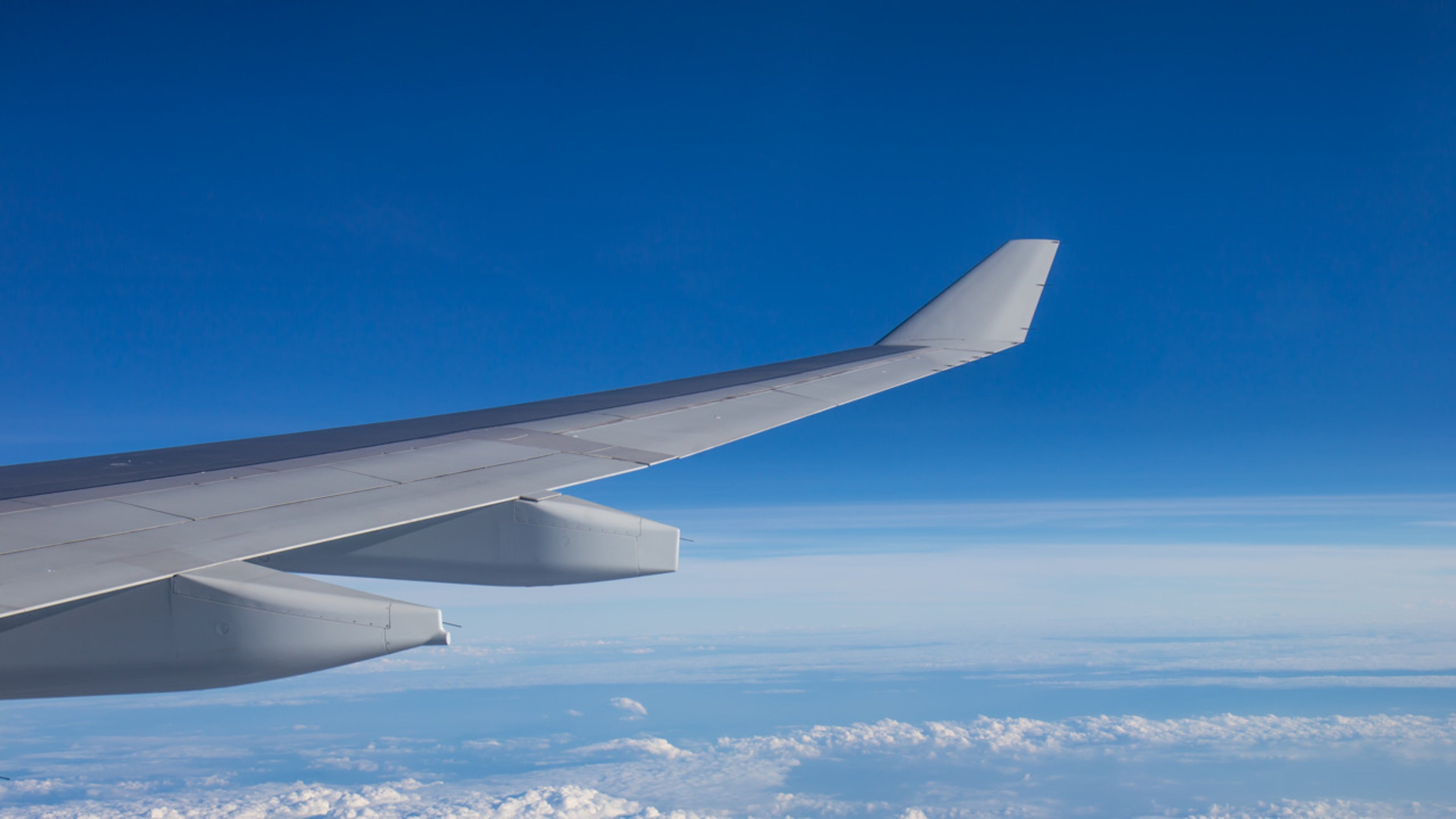 Airplane wing against blue sky with clouds