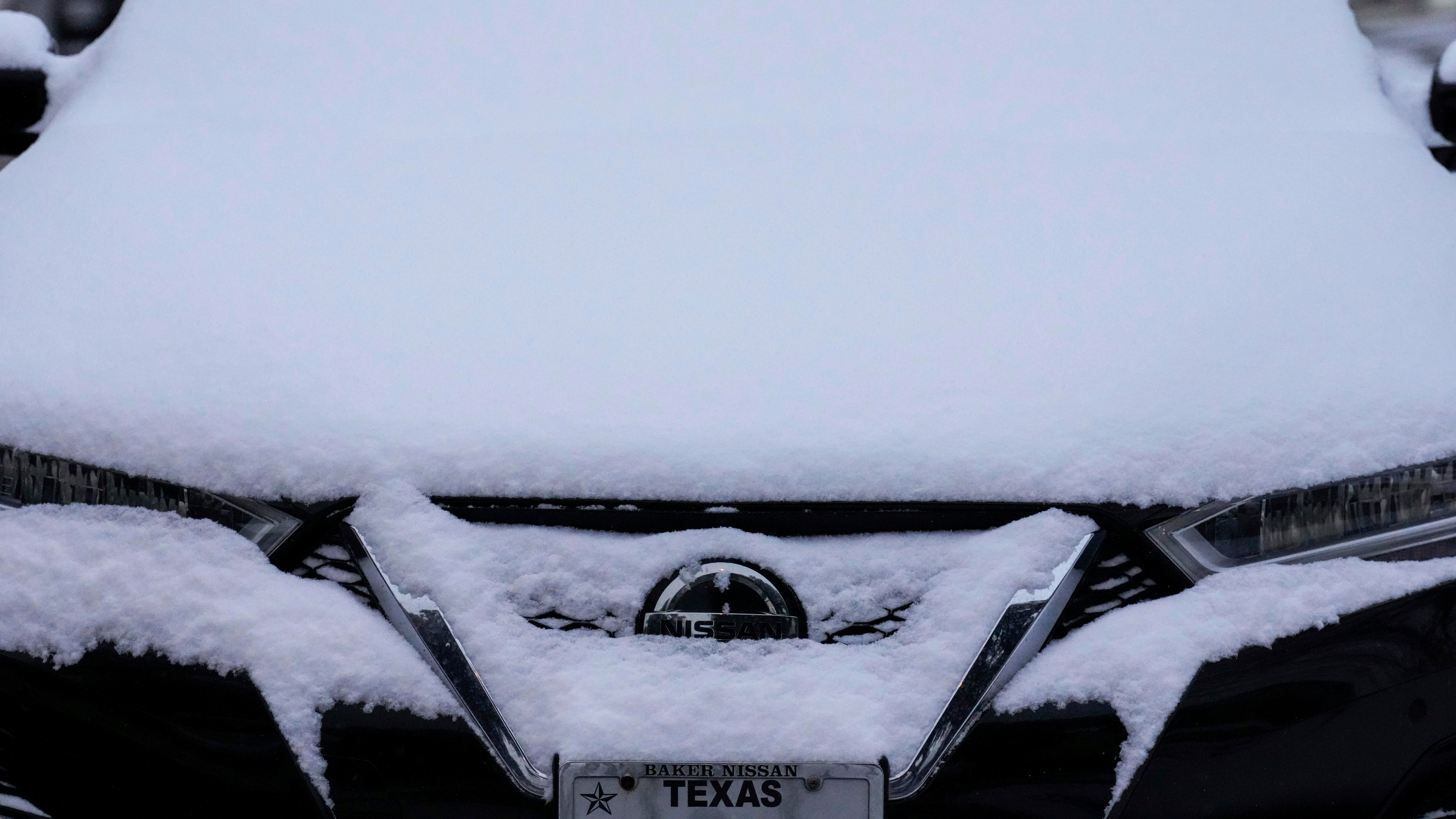 A closeup of a car covered in snow. 