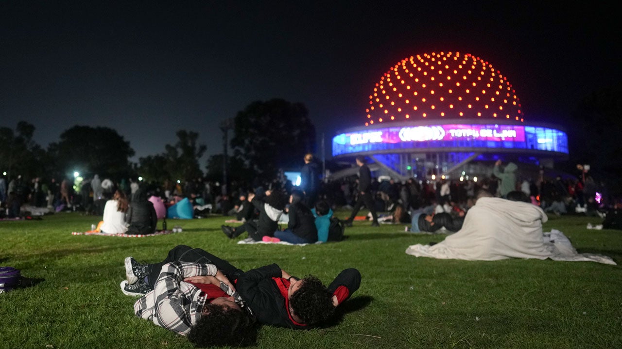 People lying on the grass and looking up at the sky during a total lunar eclipse