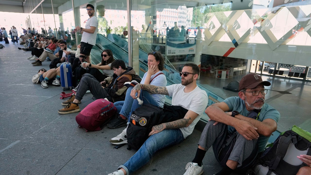 People sit on the ground at a train station during a power outage