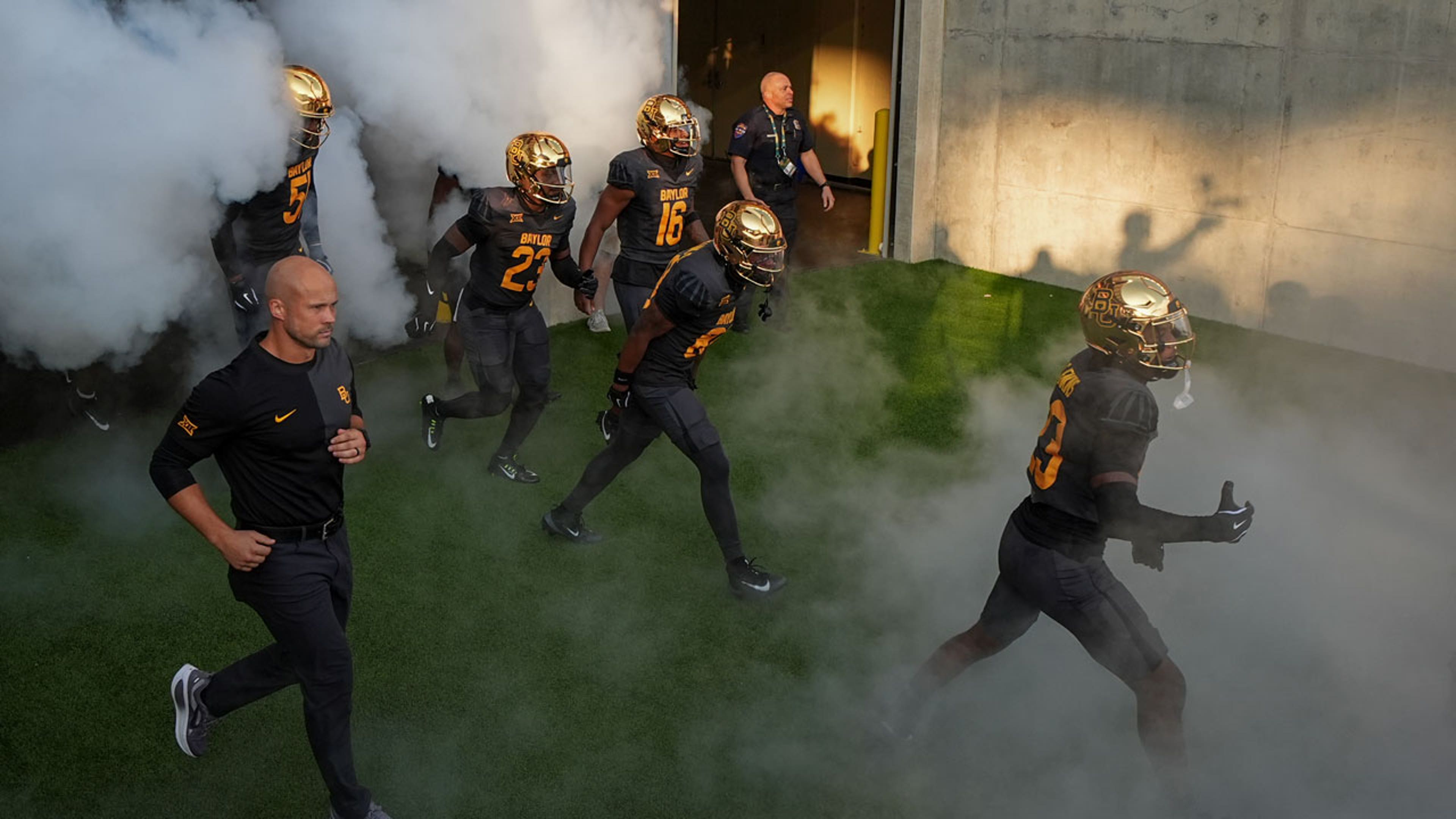 Football players run through smoke in all black uniforms