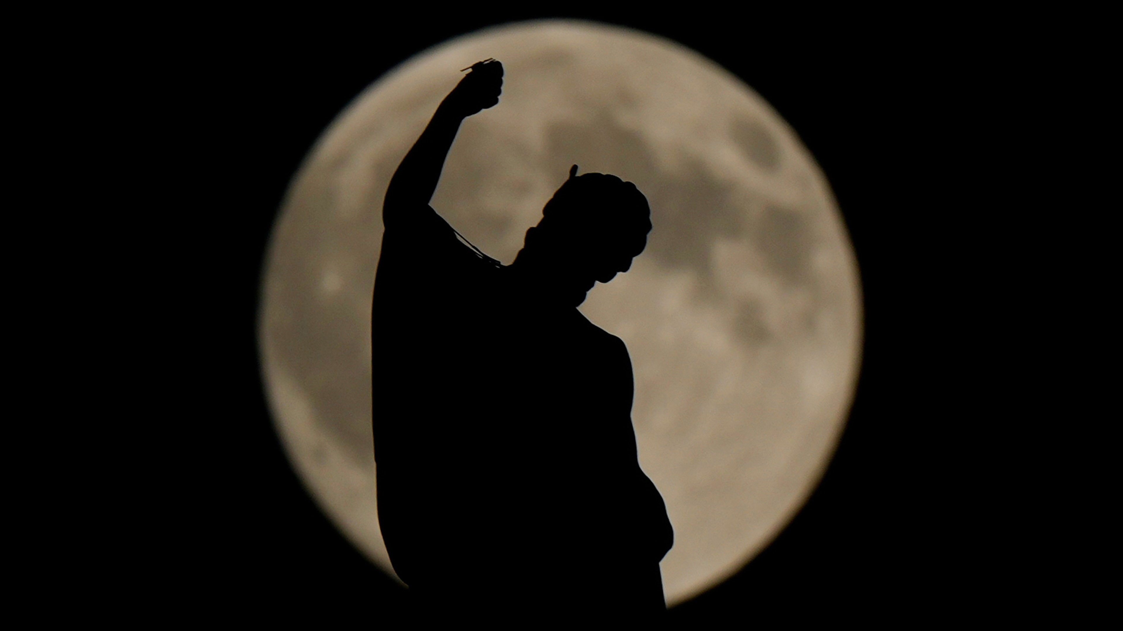 The harvest supermoon rises behind an arrow from the Gothic Duomo cathedral in Milan, Italy.