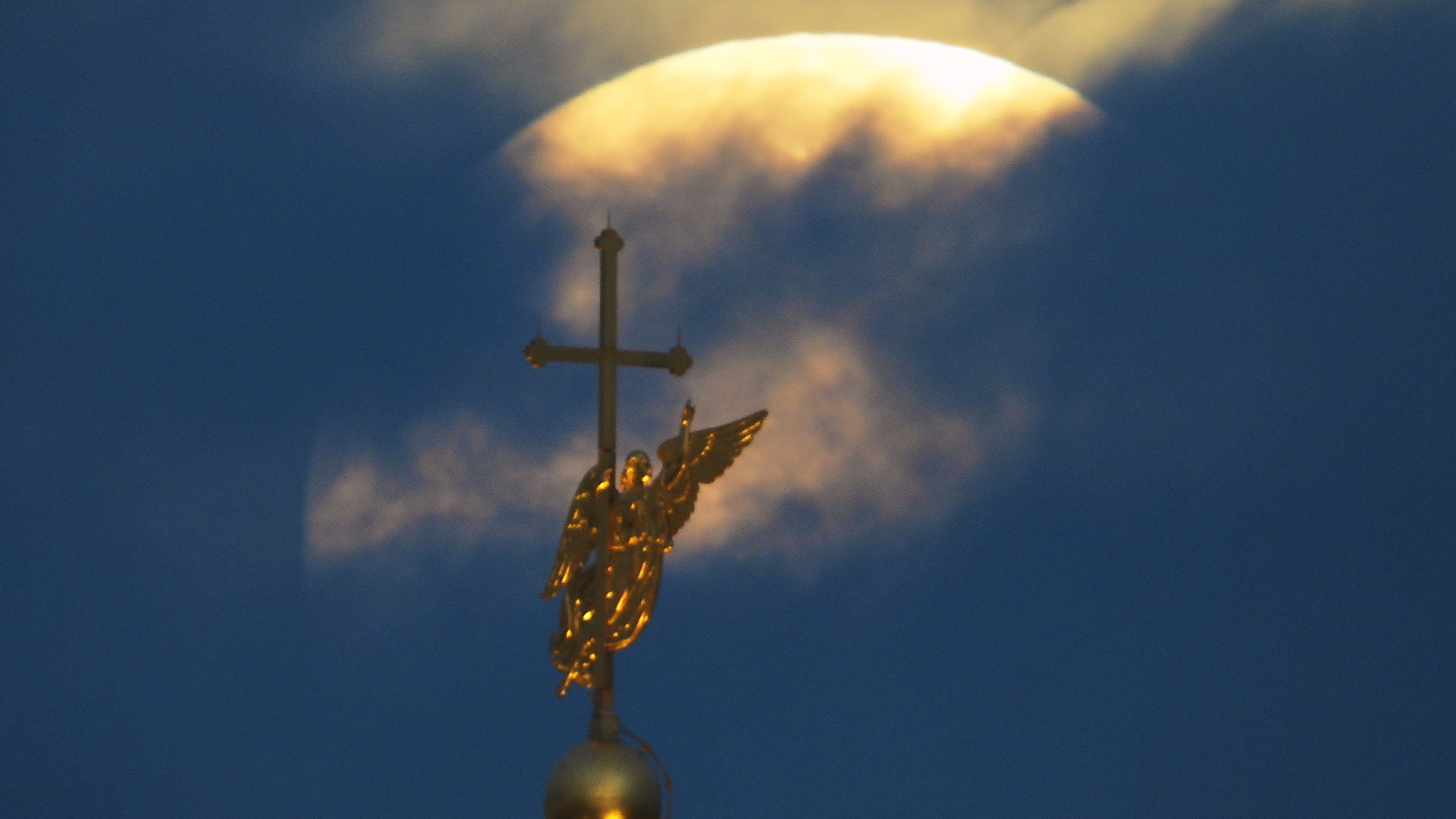 The supermoon of the harvest settles in the clouds behind a meteorological palette in the form of an angel fixed at the top of an arrow of the Saints Peter and the Paul cathedral in Saint Petersburg, in Russia.