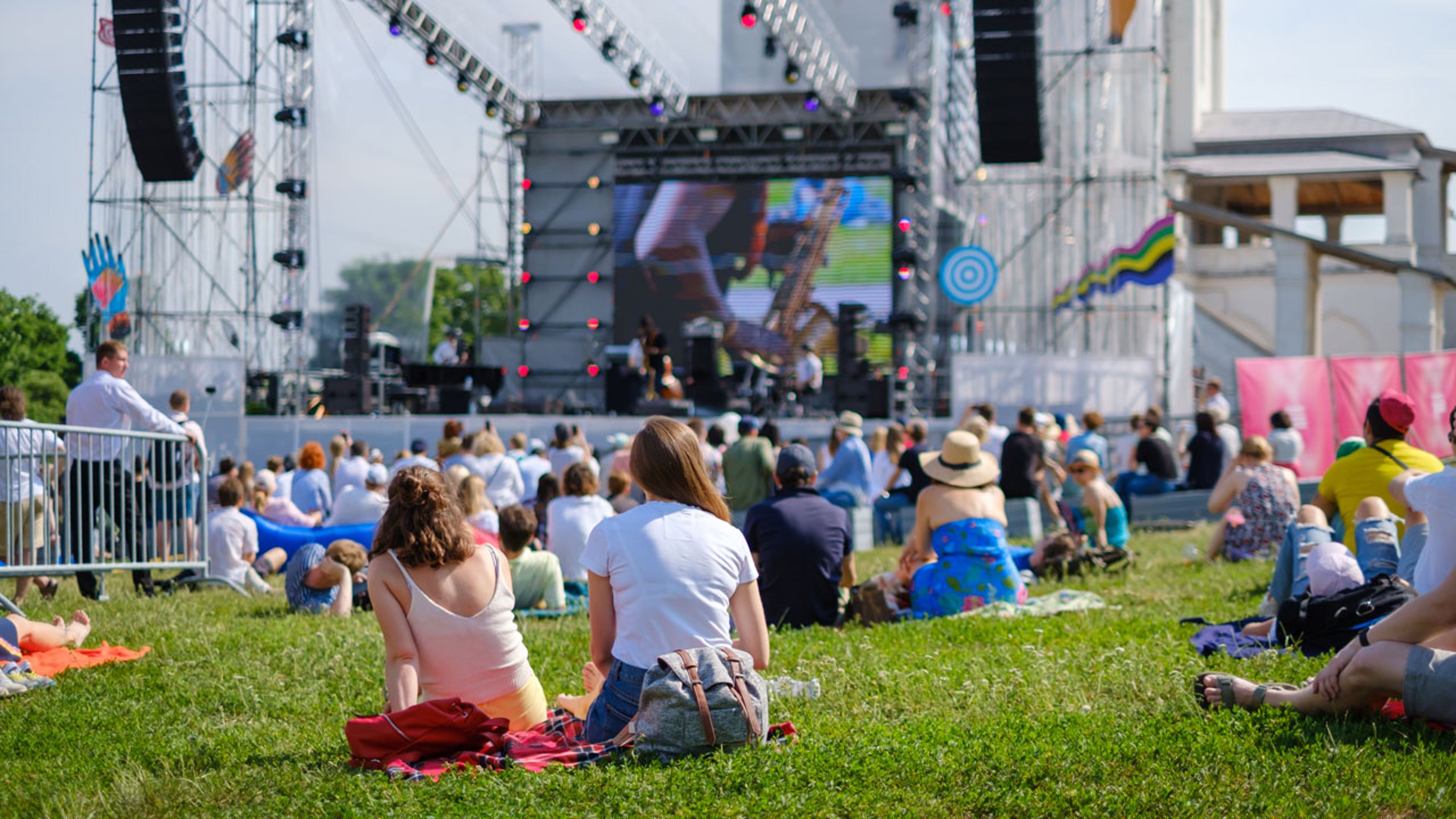 A couple sits and watches an open-air music festival