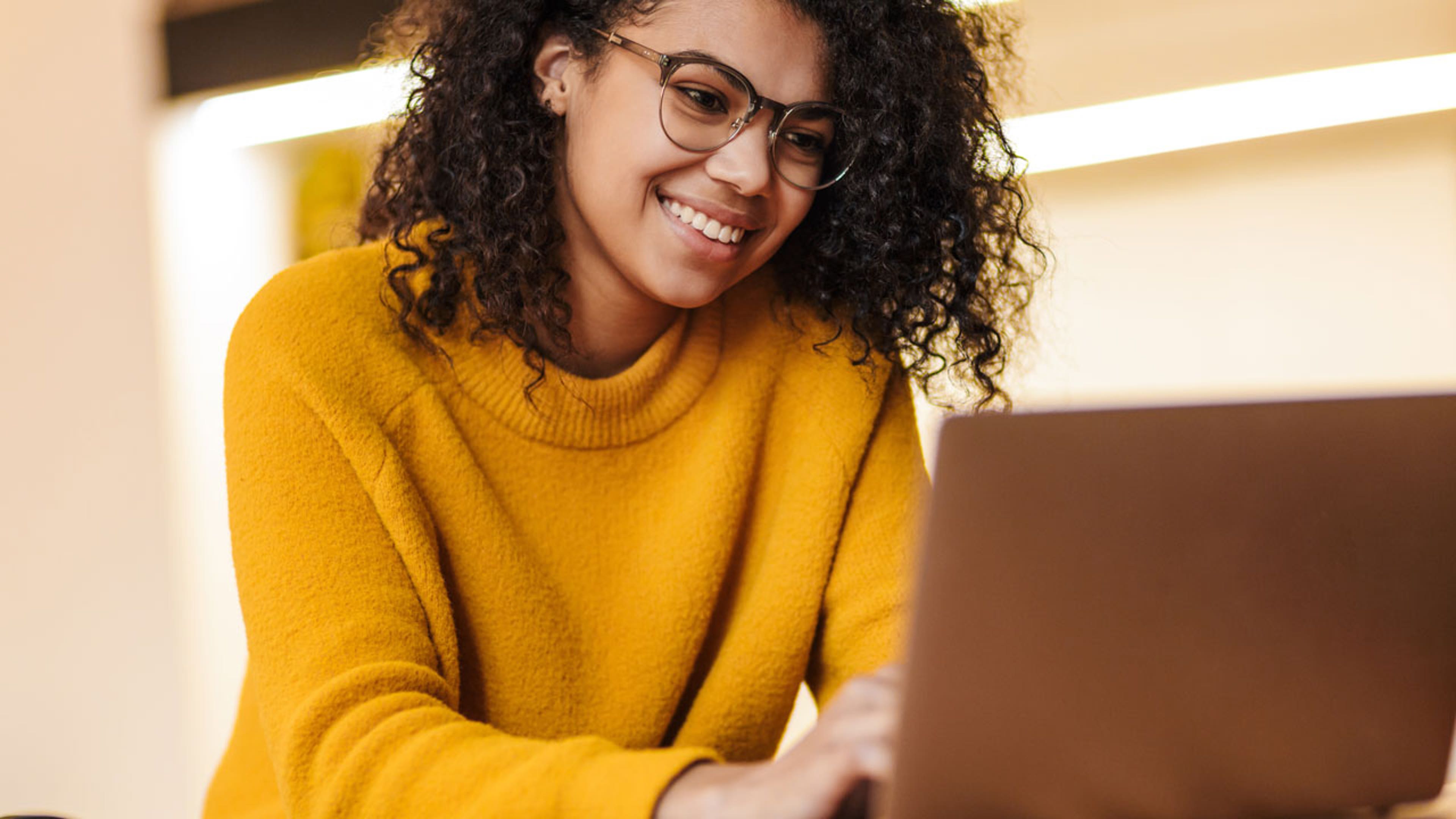 A smiling woman types on a computer
