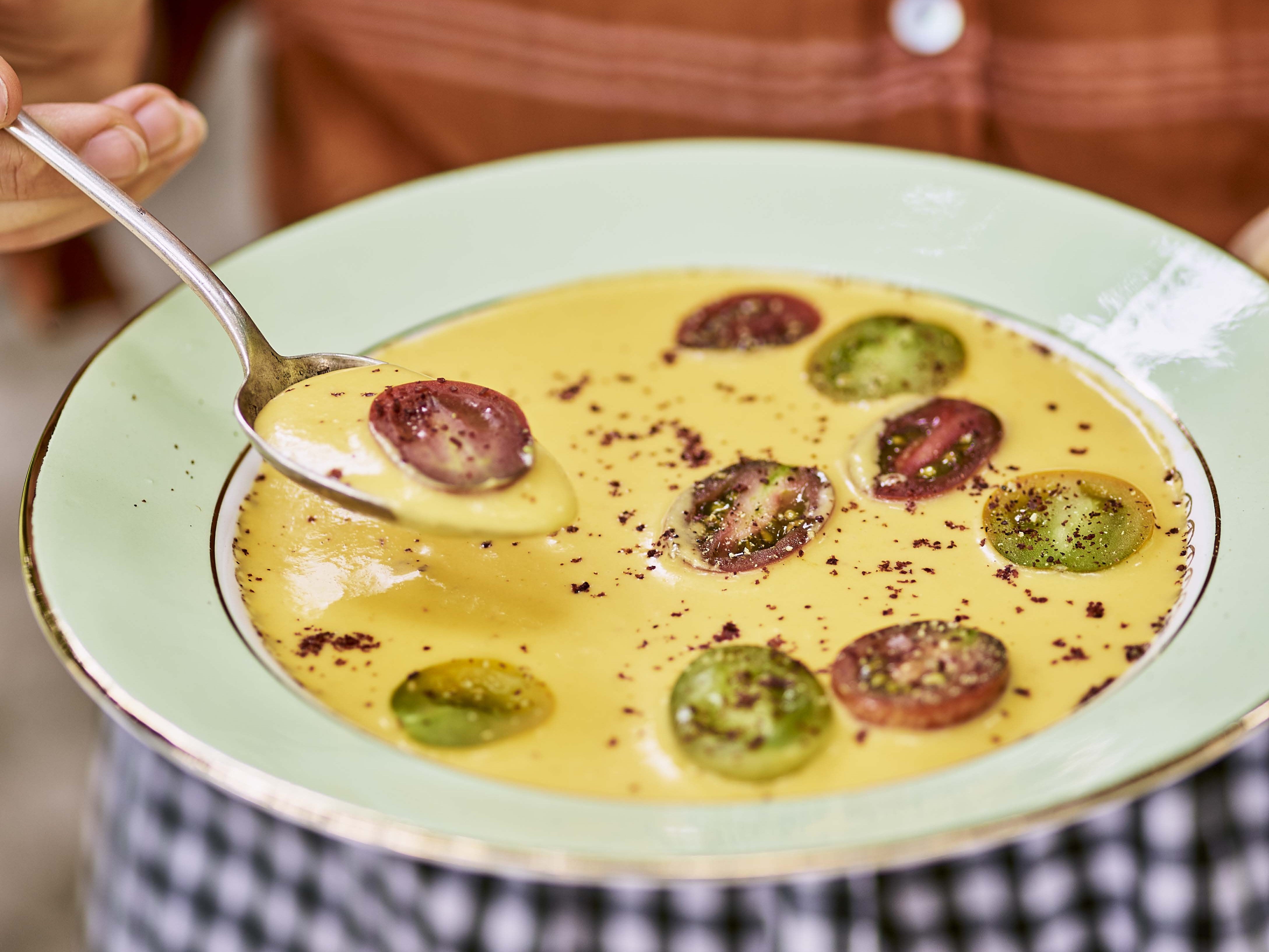 Yellow gazpacho garnished with cherry tomatoes.