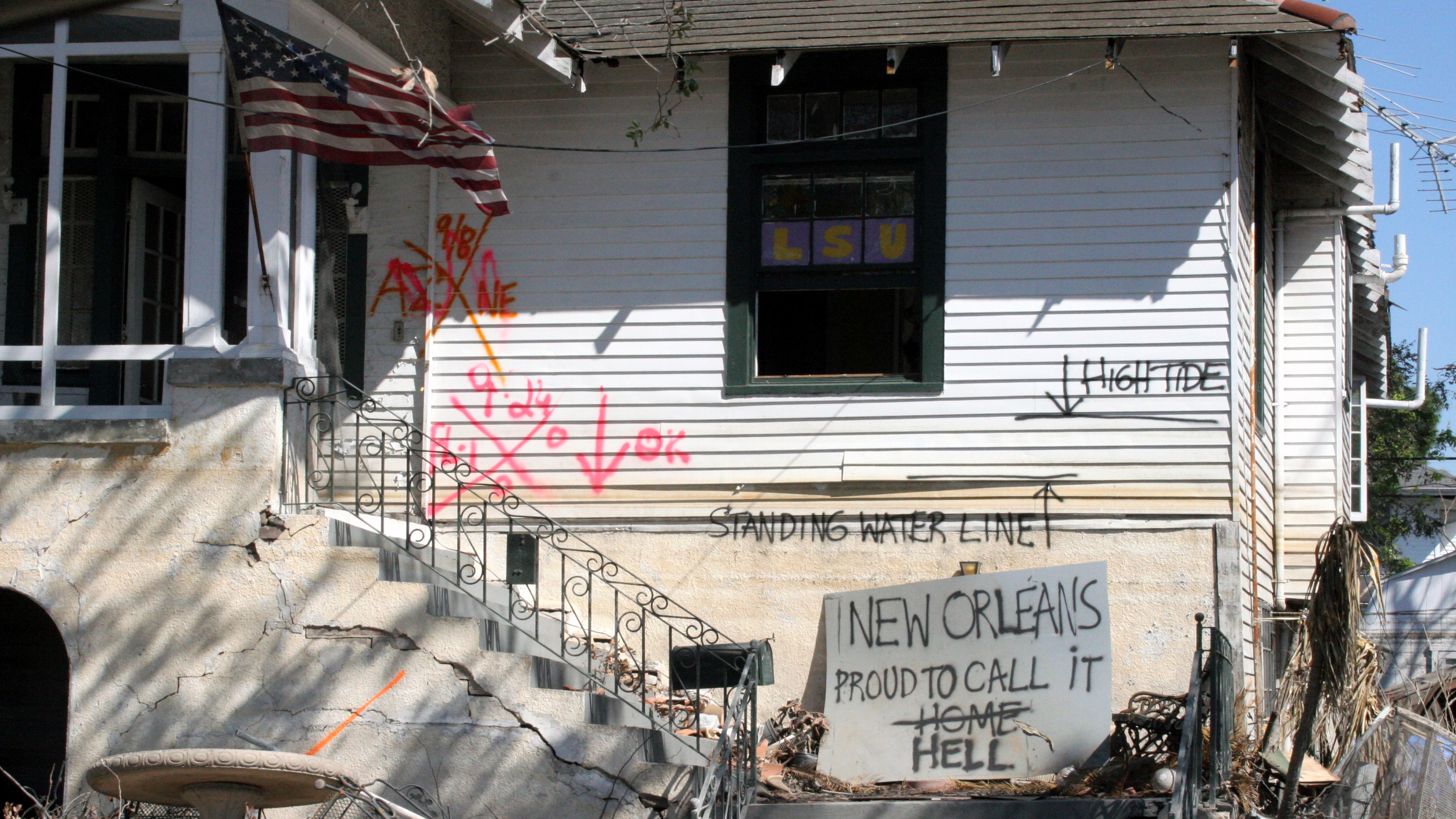 A Katrina-ravaged home bears high water scars and the spray-painted symbols of first responders.
