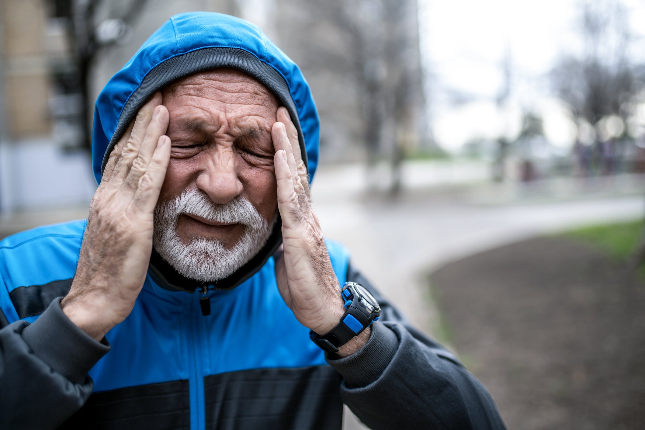 Senior sportsman having a migraine outside