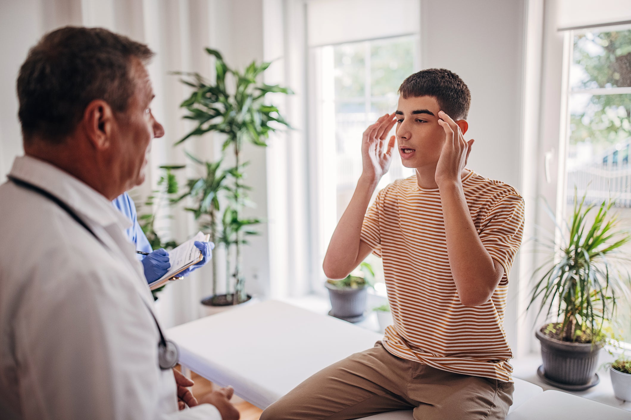 young man describing migraine pain to doctor