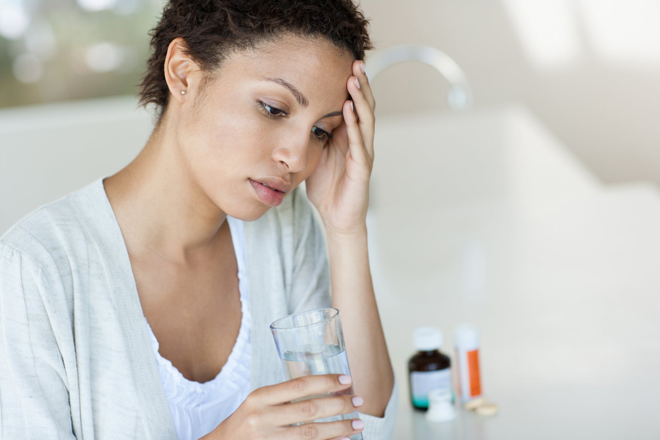 woman with migraine drinking water and taking medication