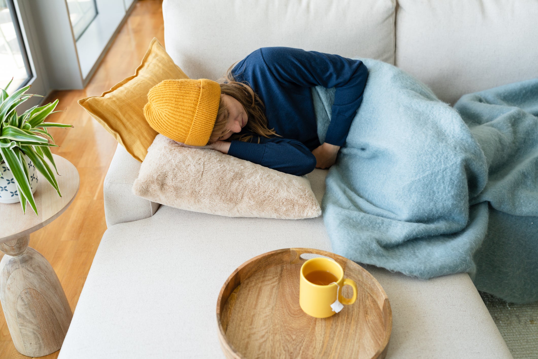 Woman lying down on sofa wearing yellow winter cap