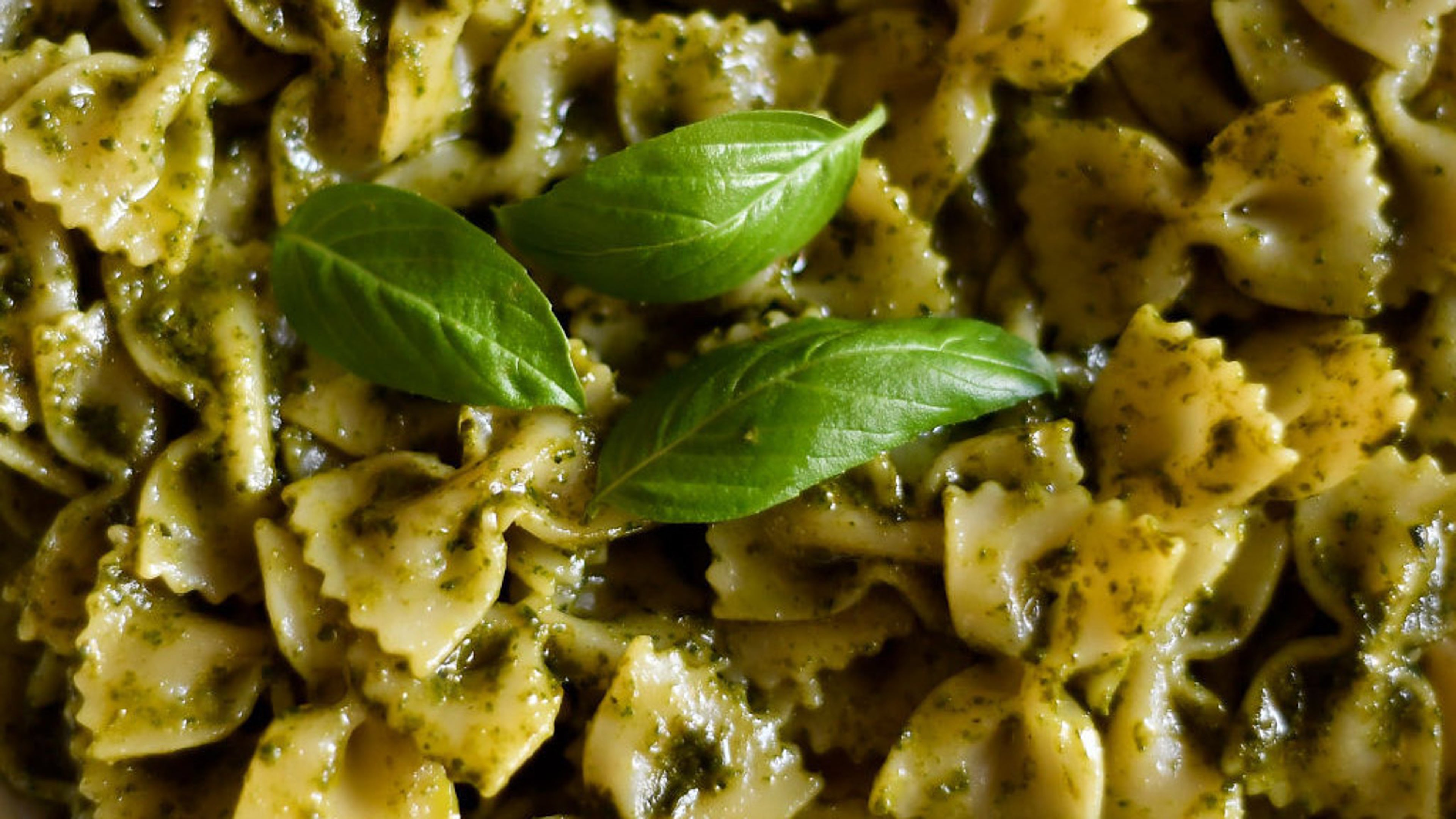 Farfalle pasta with pesto sauce and basil leaves