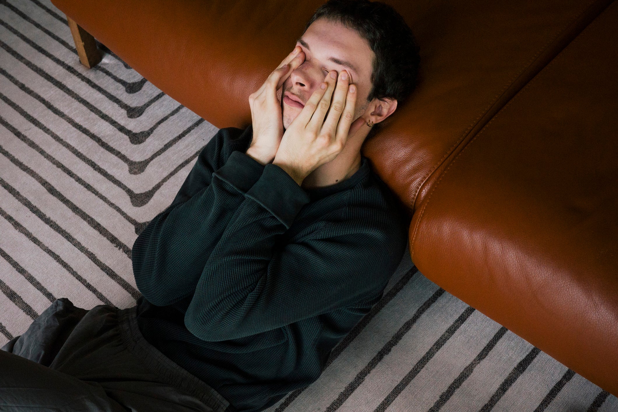 man with migraine sitting on floor