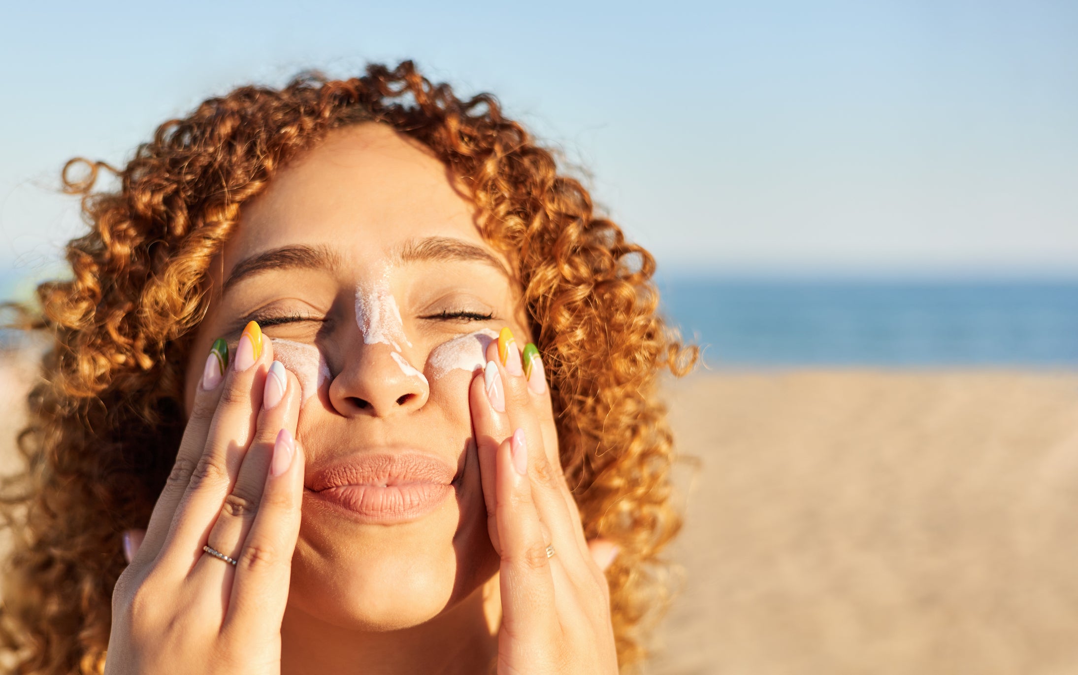 Woman applying sunscreen to her face on the beach