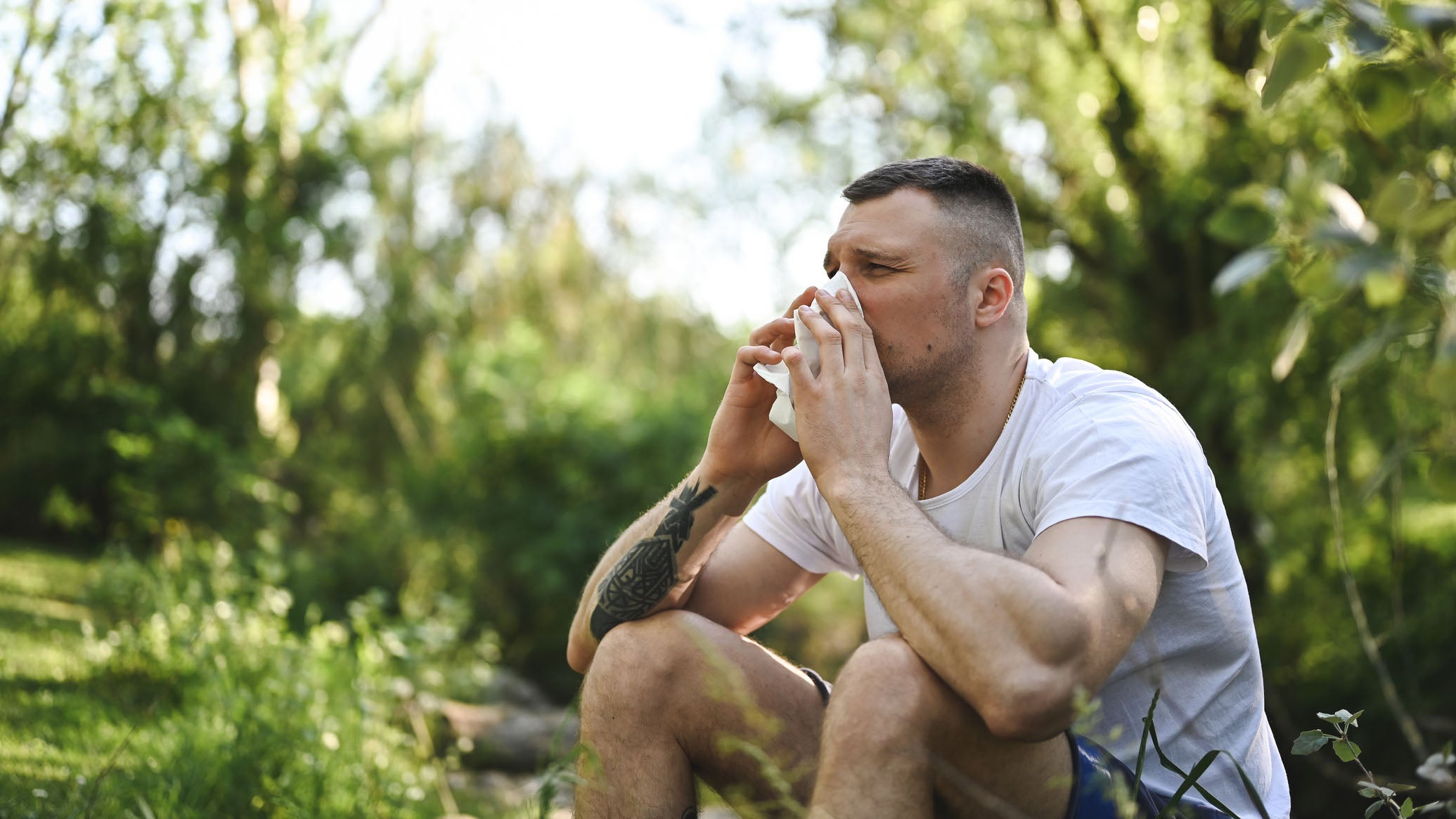 Man blows his nose outdoors.