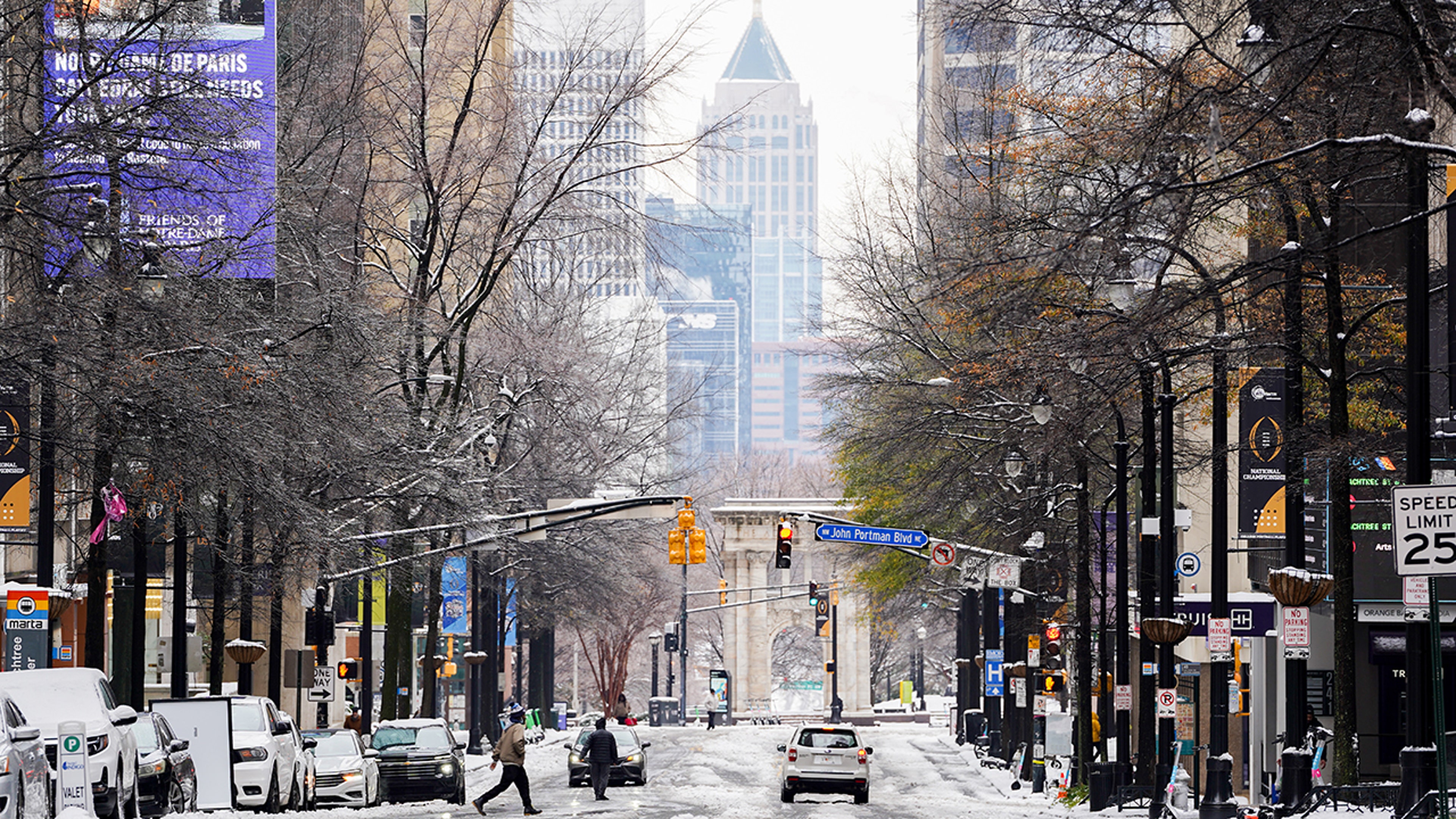 Atlanta roads are snow covered as cars drive through and people walk the streets.