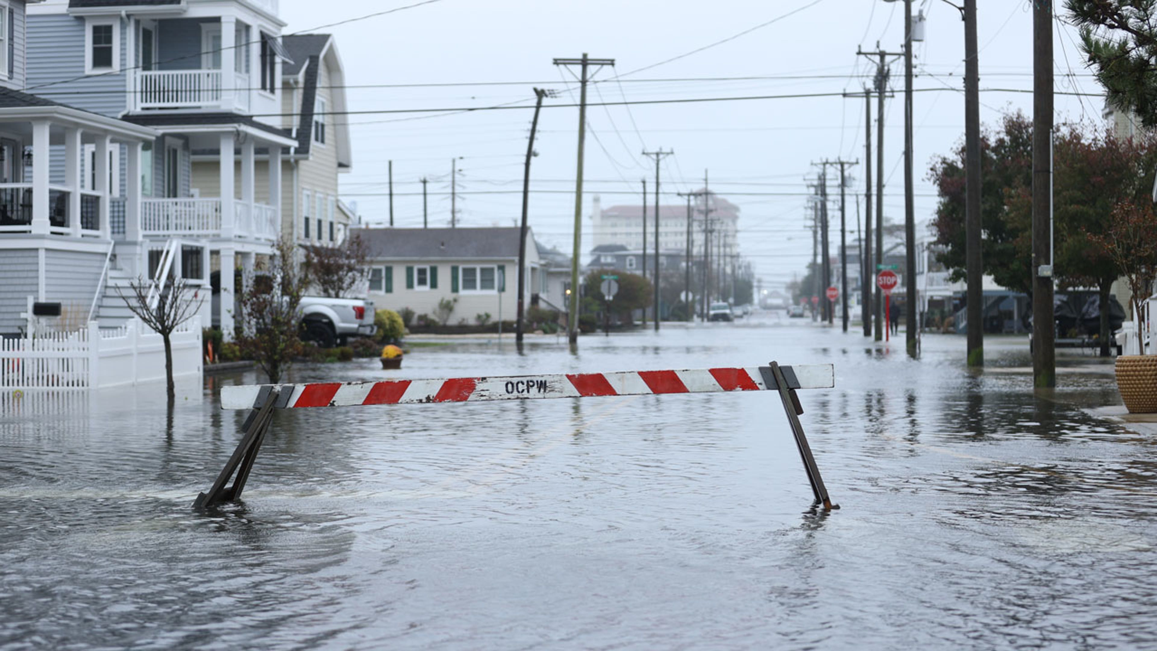 An orange and white barrier sits in the middle of a flooded road