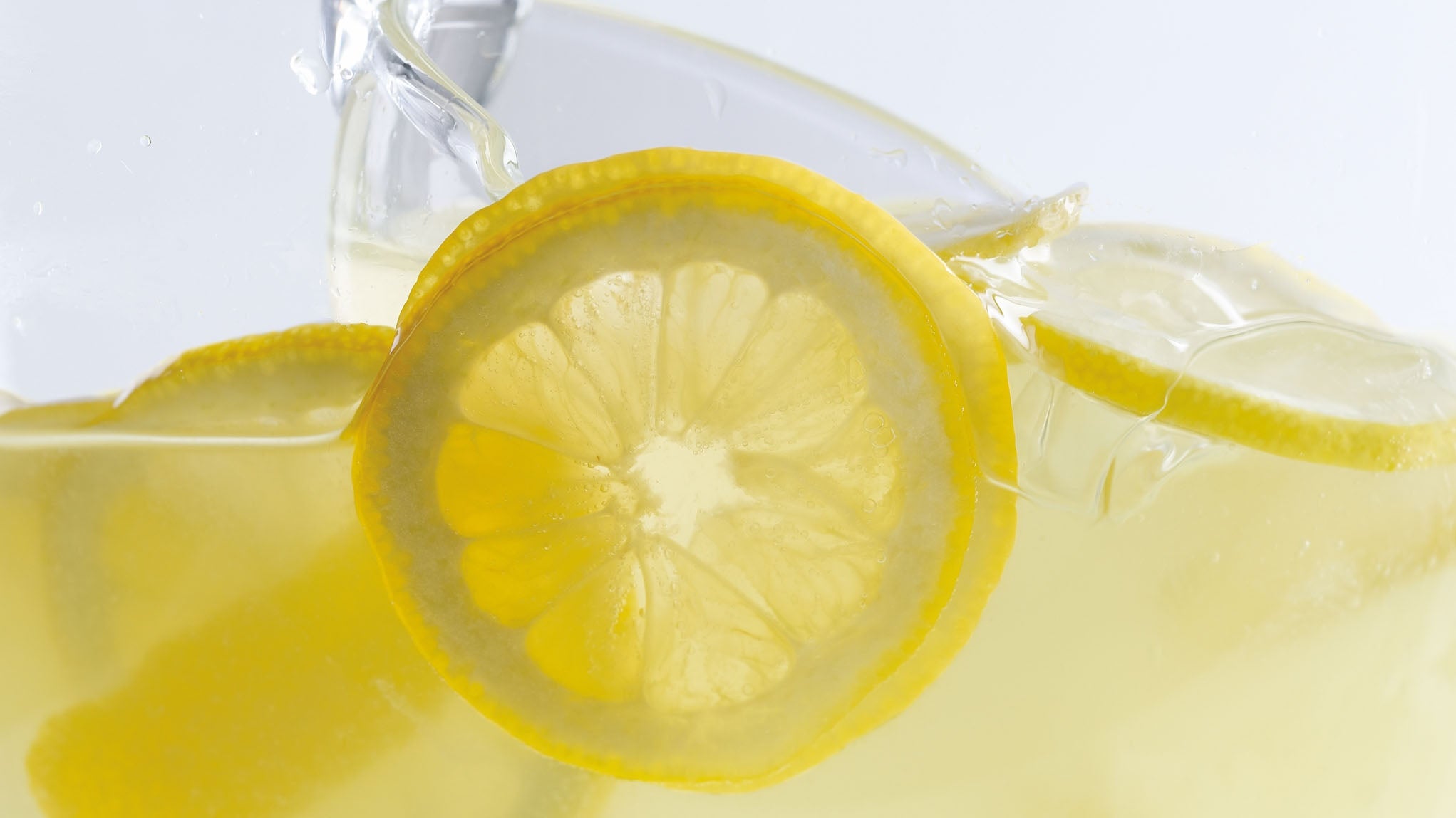 Photo shows sliced lemons in glass filled with ice and lemonade