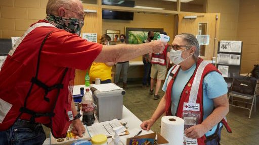 American Red Cross shelter manager Matt Albritton checks the temperature of new shelter workers that arrived to take over for a team that had been working in the shelter since before the storm struck on September 16, 2020. Photo by Jaka Vinsek/American Re