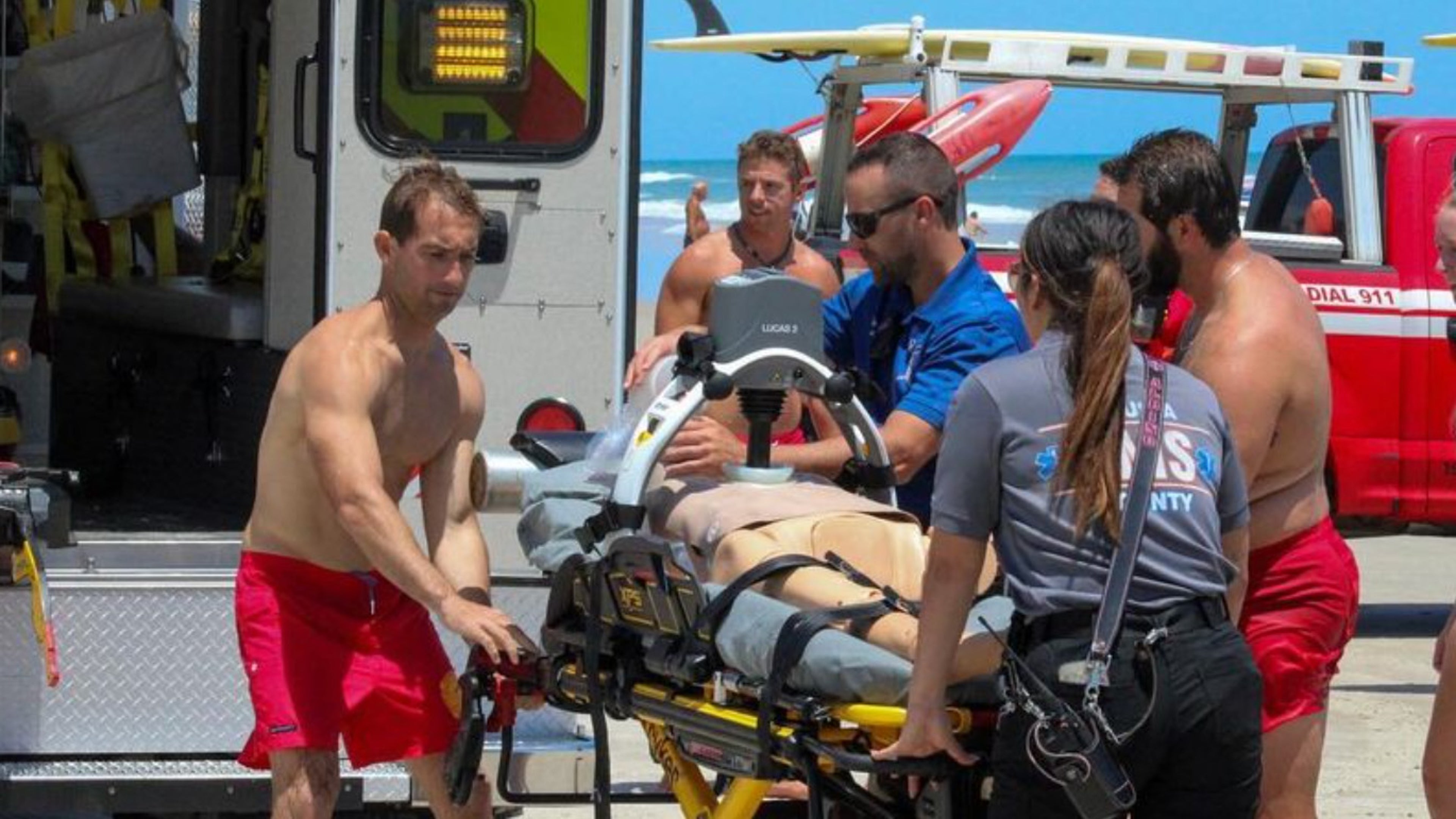 Lifeguards and EMS load an ambulance during an exercise on the beach.