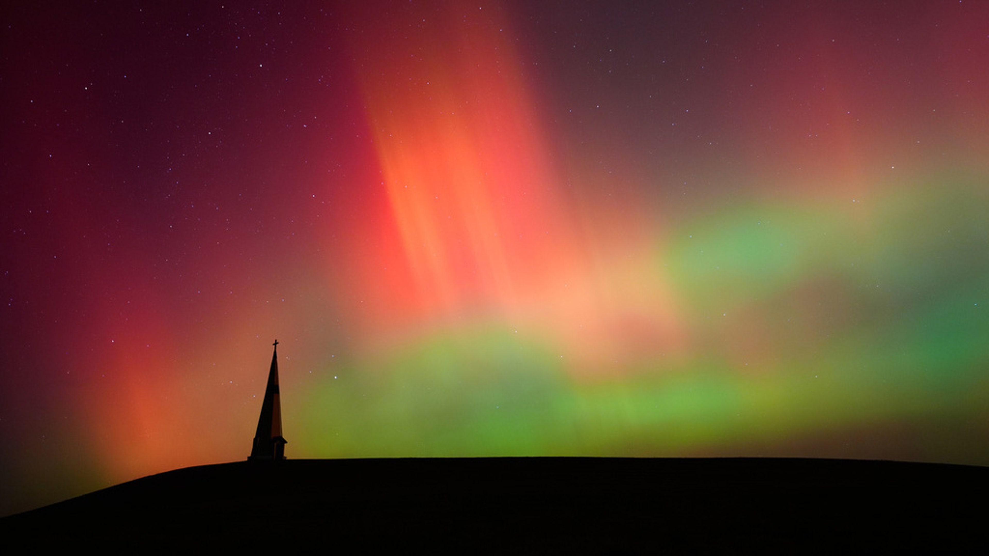 The northern lights fill the sky behind the Saint Joseph the Woodworker Shrine Tuesday, Nov. 11, 2025, near Valley Falls, Kan. 
