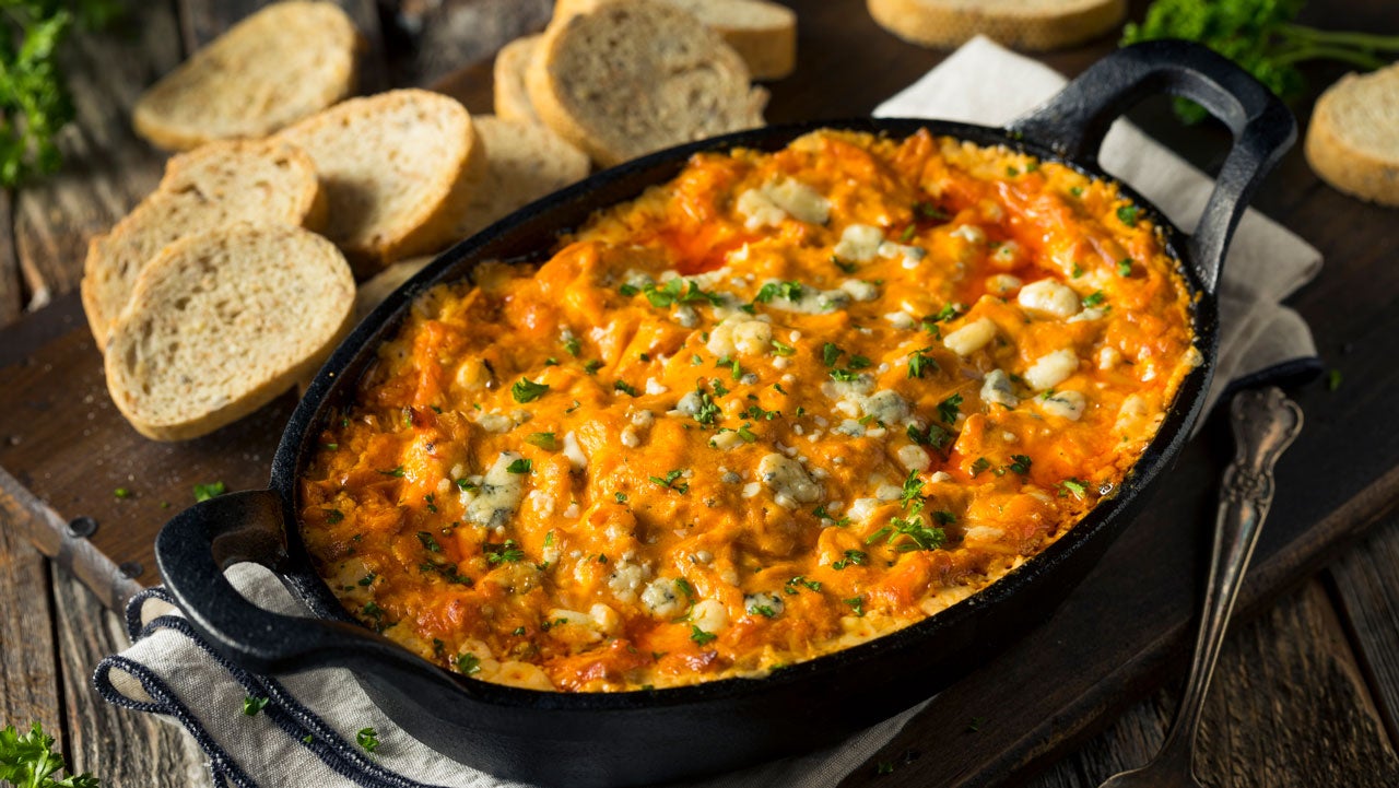 Buffalo chicken dip in cast iron casserole dish surrounded by slices of bread
