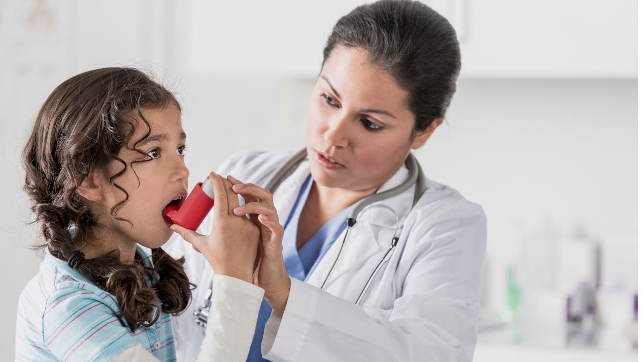 Young female patient gets asthma inhaler guidance from doctor