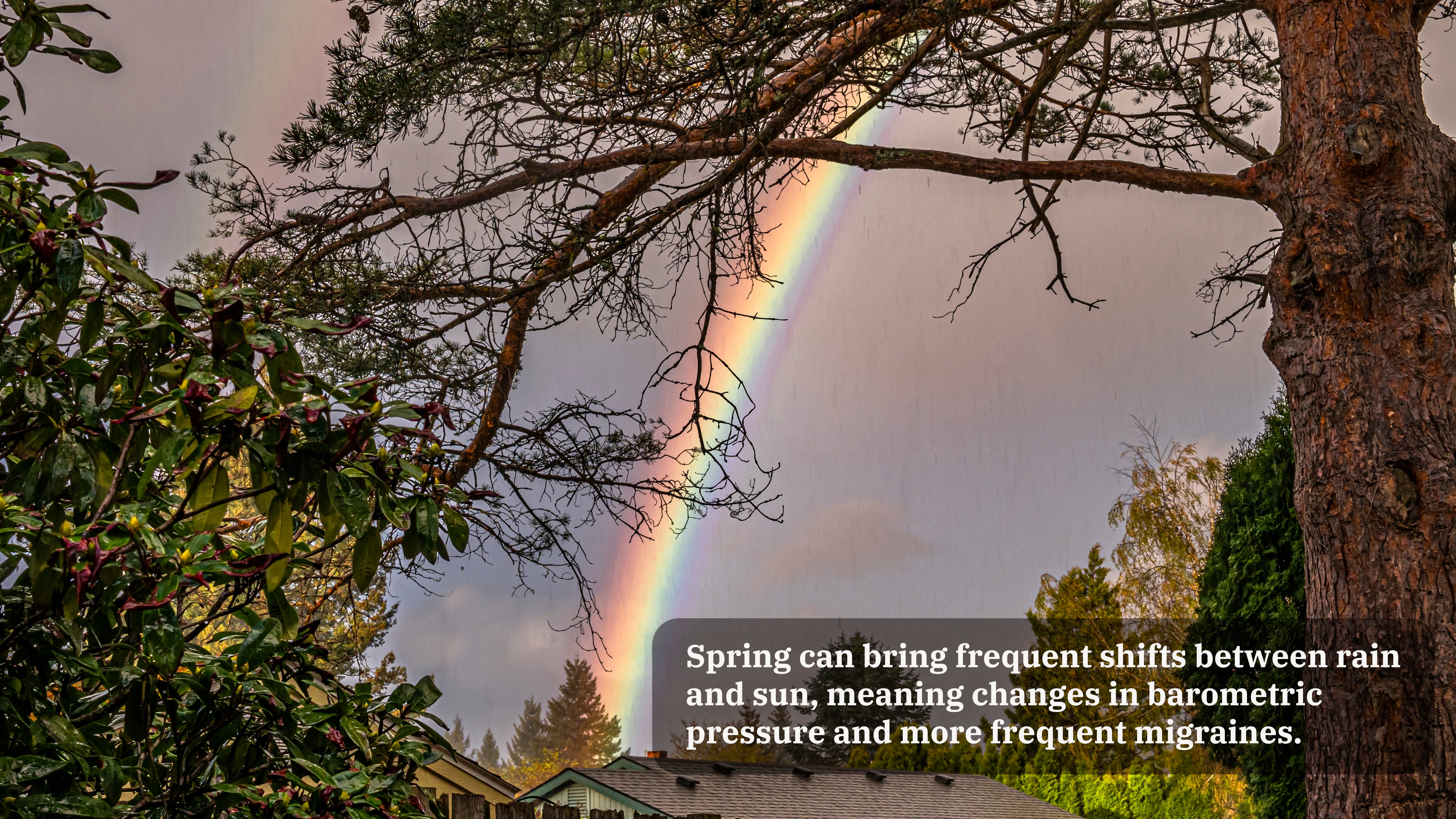 A rainbow is seen through trees. A caption on the image reads, "Spring can bring frequent shifts between rain and sun, meaning changes in barometric pressure and more frequent migraines."