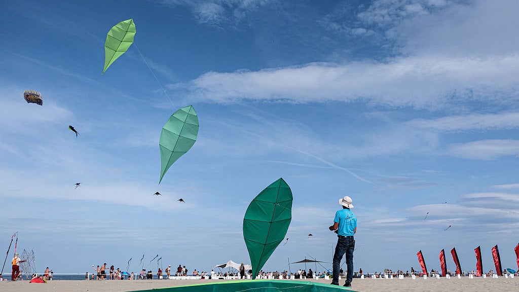 people fly kites above an Italian beach