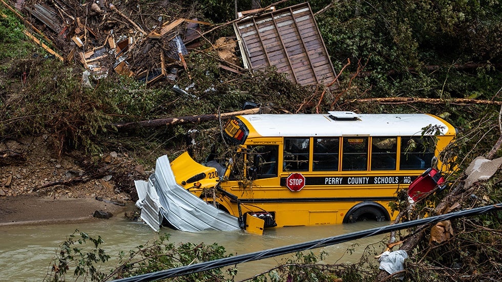 A Perry County school bus, along with other debris, sits in a creek near Jackson, Ky., on July 31, 2022. Rescuers in Kentucky are taking the search effort door-to-door in worsening weather conditions as they brace for a long and grueling effort to locate 