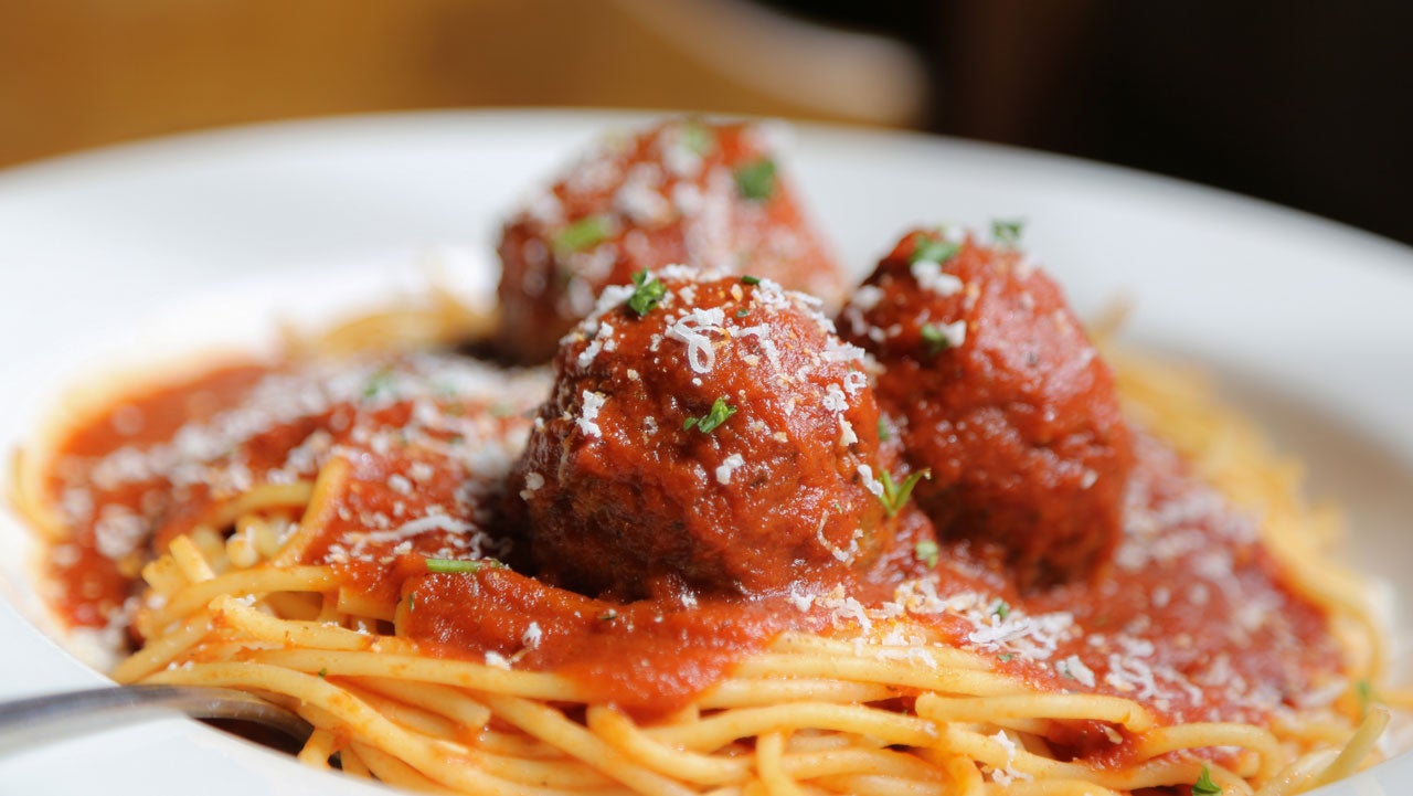 close up of spaghetti and meatballs in a white bowl