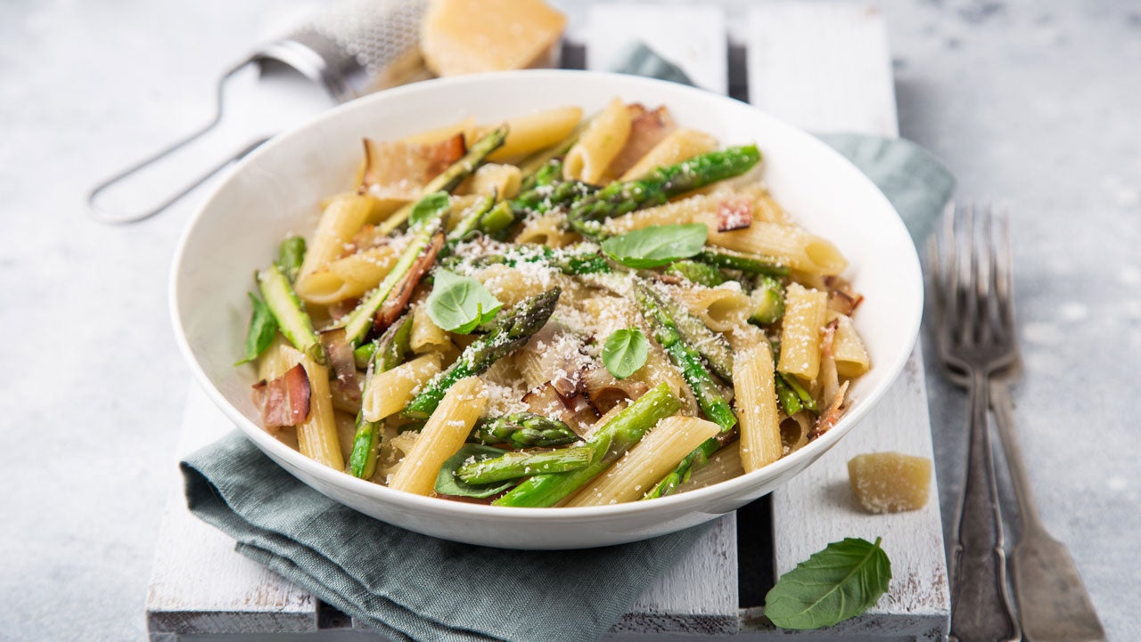 Bowl of pasta primavera with utensils and napkins