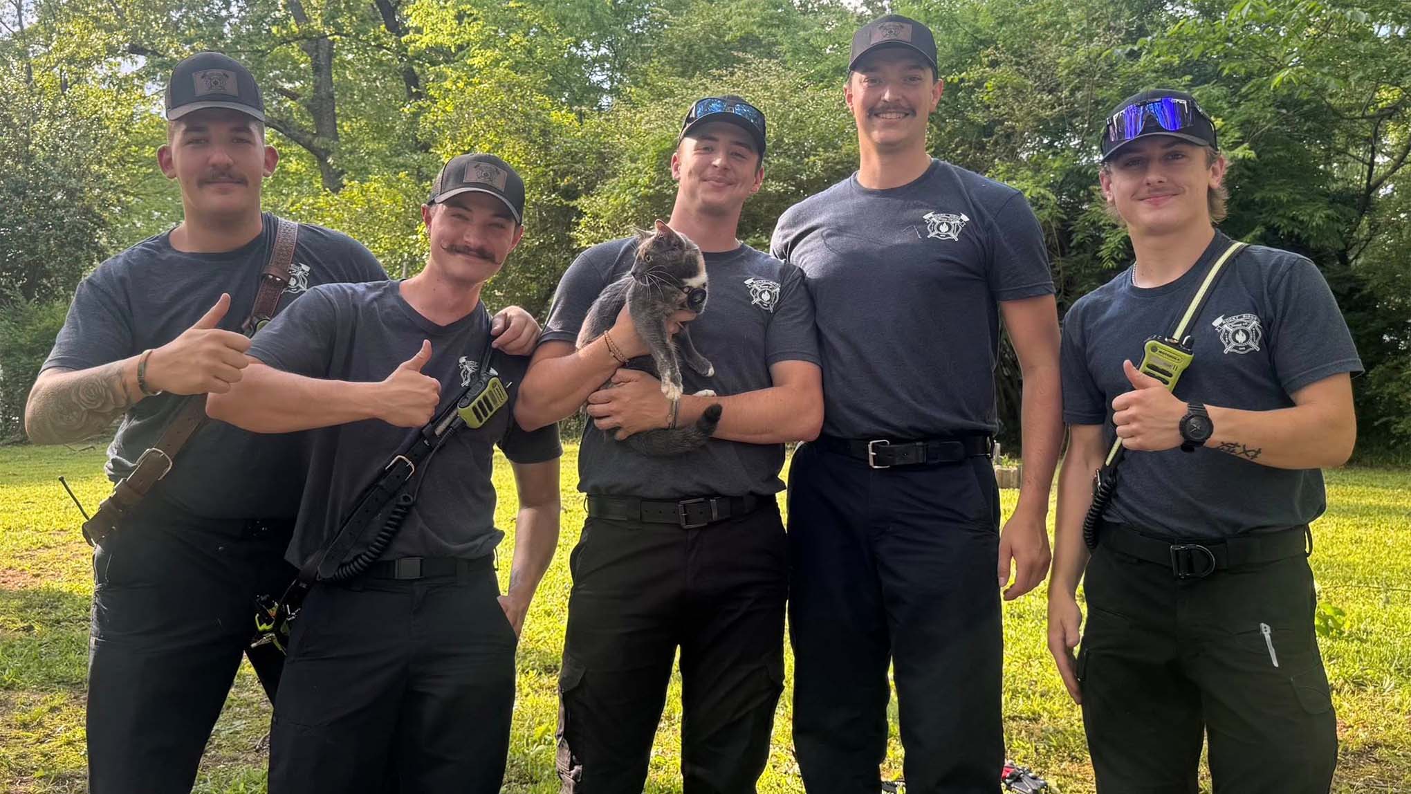 A group of firefighters holding a rescued cat. 