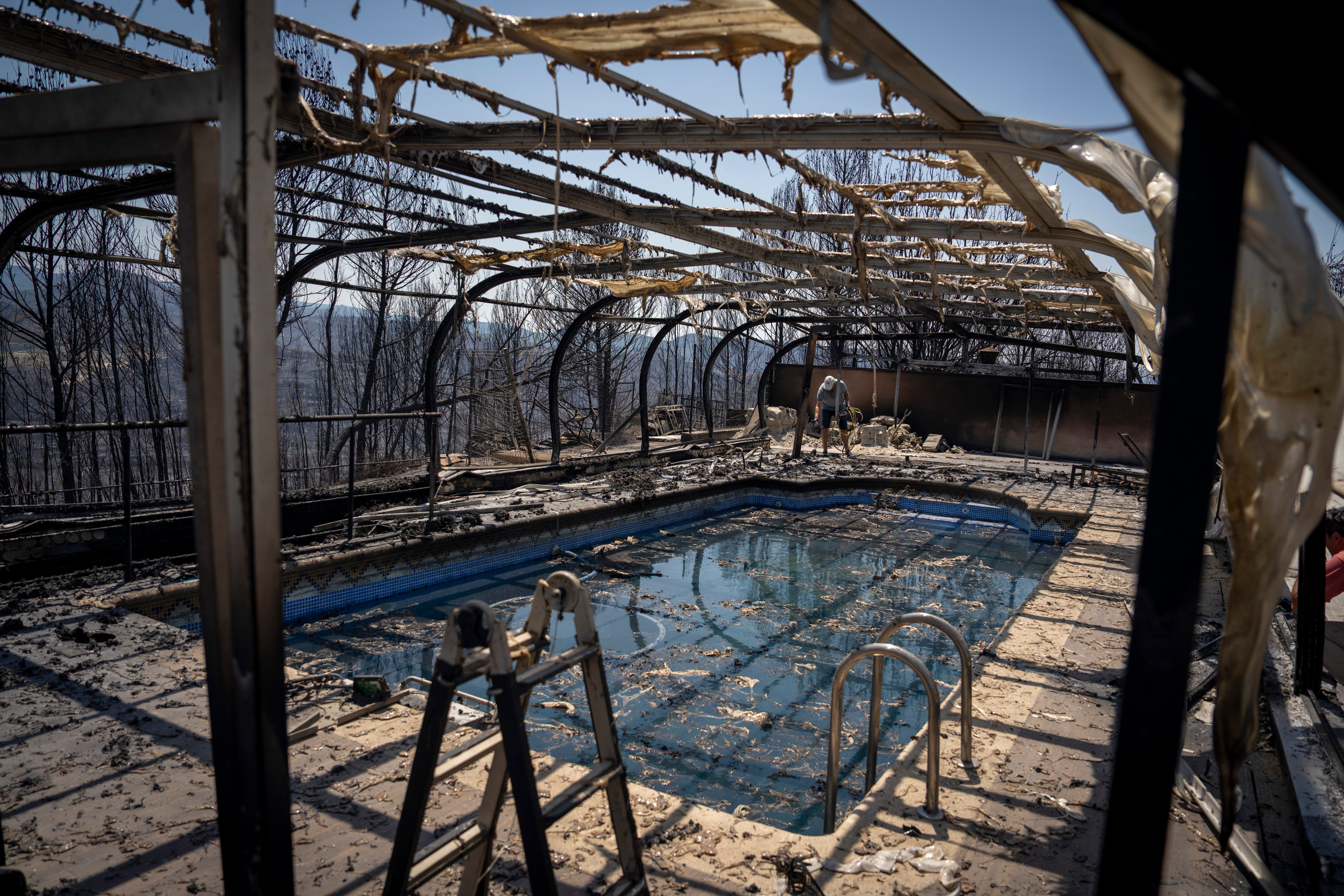Jaume Almirall checks the damage to his swimming pool which burnt during a wildfire near the town of El Pont de Vilomara, Spain, Tuesday, July 19, 2022. Hundreds of residents evacuated by a wildfire in Bages, in northeastern Spain were anxious to get back to their homes and assess the extent of the damage. Authorities in Catalonia deployed dozens of firefighting planes and helicopters to try and contain the spreading fire that ravaged several homes and burnt more than six square miles. (AP Photo/Emilio Morenatti)
