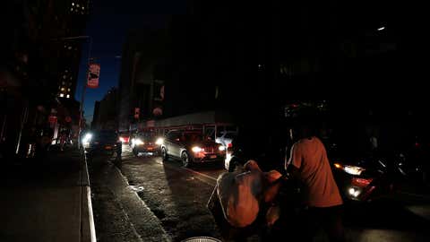 A man makes his way through a dark Times Square during a power outage, Saturday, July 13, 2019, in New York. (AP Photo/Michael Owens)