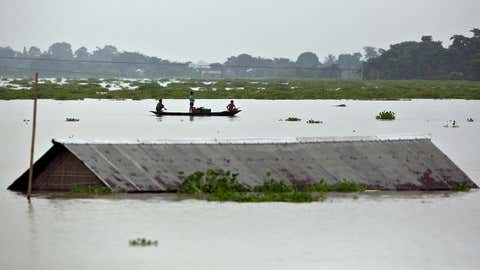 Flood affected villagers row near a submerged house in the flood water in Burha Burhi village east of Gauhati India, Monday, July 15, 2019. After causing flooding and landslides in Nepal, three rivers are overflowing in northeastern India and submerging parts of the region, affecting the lives of more than 2 million, officials said Monday.(AP Photo/Anupam Nath)