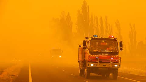 Fire burns in the grass along the road as firetrucks pass by near Bumbalong, south of the Australian capital, Canberra, Saturday, Feb. 1, 2020. The threat is posed by a blaze on Canberra's southern fringe that has razed more than 21,500 hectares (53,000 acres) since it was sparked by heat from a military helicopter landing light on Monday, the Emergency Services Agency said. (AP Photo/Rick Rycroft)