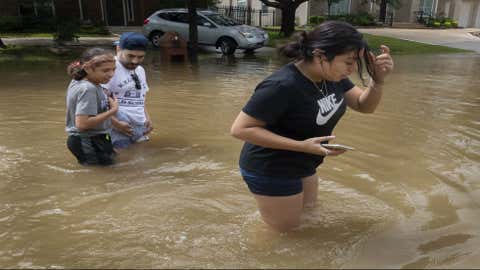 Jazmin Trejo, right, walks through a flooded section of Appleblossom Lane with her sister Lilly Trejo and father Marcus Trejo in Friendswood, Texas, on Tuesday, Sept. 22, 2020, following Tropical Storm Beta. (Stuart Villanueva/The Galveston County Daily News via AP)